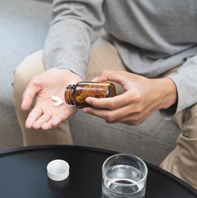 Sick,Asian,Young,Man,,Male,Holding,Tablet,Pill,On,Hand,