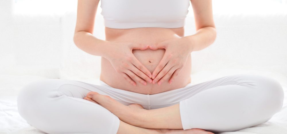 Pre-natal exercises. Beautiful pregnant woman exercising while sitting in lotus position